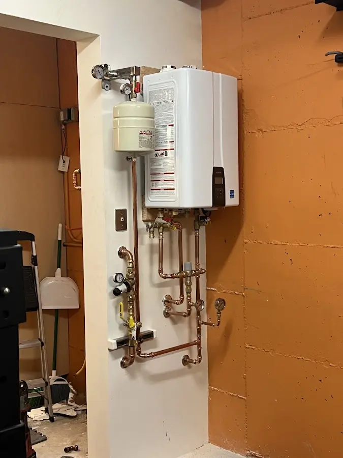 Plumbing technician inspecting water heater connections in Rensselaer